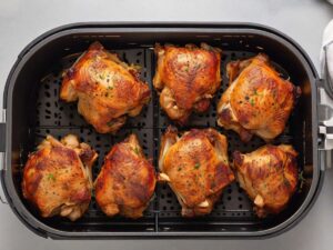 Marinated chicken thighs placed inside the air fryer basket