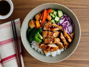 Assembling air fryer chicken teriyaki bowl with vegetables and sauce