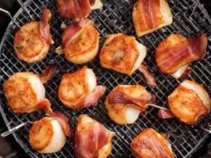 Flipping bacon-wrapped scallops halfway through cooking