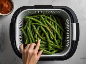 Placing seasoned green beans in the air fryer basket
