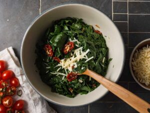 Mixing spinach, mozzarella, sun-dried tomatoes, and garlic for filling