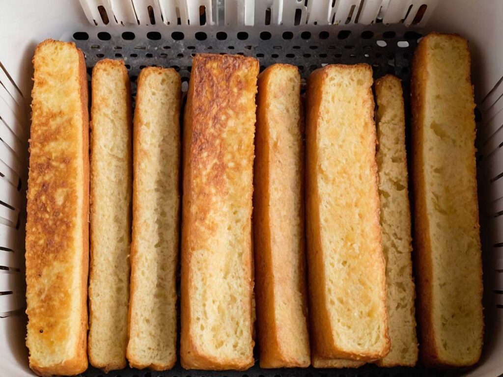 Arranging frozen French toast sticks in air fryer basket